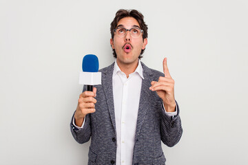 Young hispanic TV presenter man isolated on white background pointing upside with opened mouth.