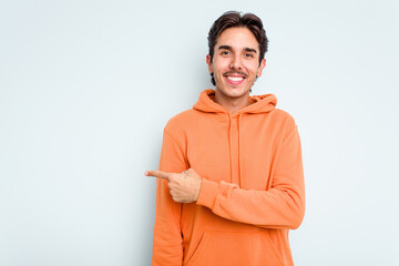 Young hispanic man isolated on blue background smiling and pointing aside, showing something at blank space.