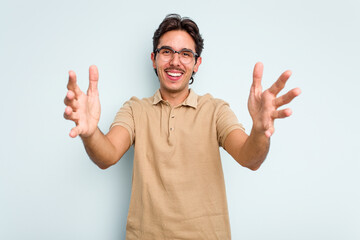 Young hispanic man isolated on blue background celebrating a victory or success, he is surprised and shocked.