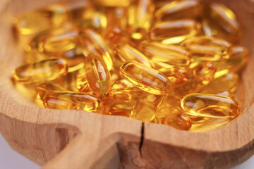 Yellow Omega 3 capsules in a cracked wooden bowl. Health Supplement
