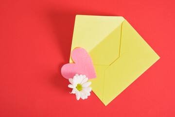 mock up yellow envelope and pink felt heart on red background