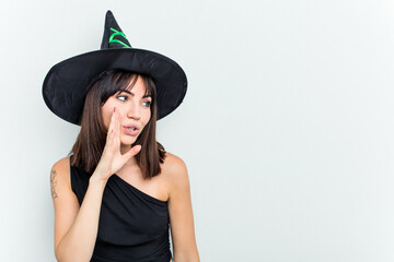 Young caucasian woman dressed as a witch isolated on white background is saying a secret hot braking news and looking aside