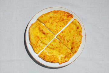 Puff pastry khachapuri with suluguni cheese. Round khachapuri. The food lies on a light, round ceramic plate. The plate is in the light. linen fabric background.
