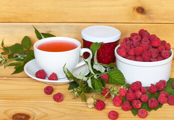 Fresh ripe garden raspberries, homemade raspberry jam and a cup with fruit compote on a wooden table. Healthy tasty food