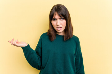 Young caucasian woman isolated on yellow background doubting and shrugging shoulders in questioning...