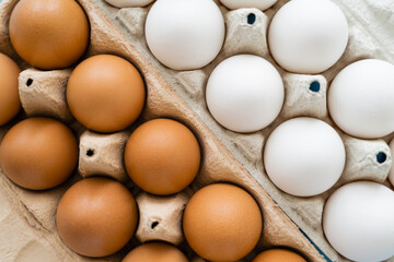 Top view of brown and white chicken eggs in carton trays.