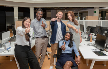 Happy multicultural business team people show thumbs up in victory sign looking at camera