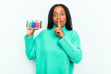 Young African American woman holding battery box isolated on blue background keeping a secret or asking for silence.