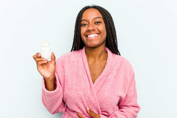 Young African American woman wearing bathrobe holding a deodorant isolated on blue background...