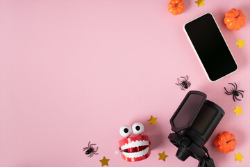 Microphone and smartphone with pumpkins and a clockwork toy with teeth on a pink background.