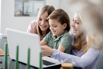 Single mother with two kids watching something on laptop