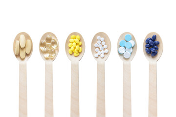 Variety of vitamin capsules and mineral pills in wooden spoon isolated on white background. Top view. Dietary supplement health care product.