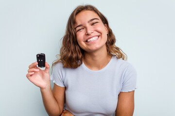 Fototapeta premium Young caucasian woman holding car keys isolated on blue background laughing and having fun.