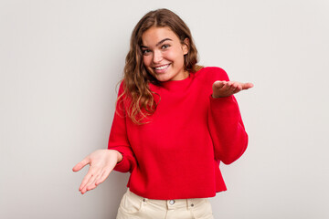 Young caucasian woman isolated on blue background makes scale with arms, feels happy and confident.