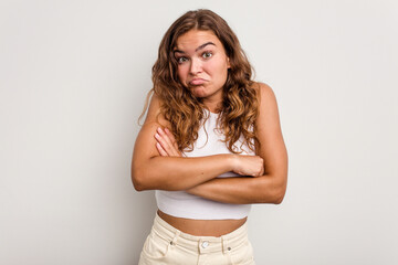 Young caucasian woman isolated on blue background shrugs shoulders and open eyes confused.