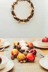Fall table setting for celebration Thanksgiving day family party. Autumn composition with candles, fruits, nuts and cones. Plates with pumpkins and pomegranate. Natural autumn decor. Selective focus