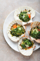 Recipe Baked sea scallops.  Recipe with chopped parsley and dry grated bread  on the white plate on the soft rose marble background, close-up, medium tone. Mediterranean seafood recipes