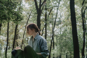Woman writing in notebook/diary in the middle of the forest