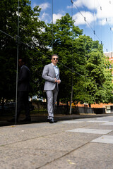 A handsome businessman in a grey suit and sunglasses in an urban city environment