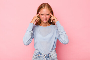 Caucasian teen girl isolated on pink background focused on a task, keeping forefingers pointing head.