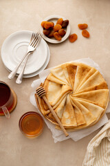Pancakes or thin crepes with honey on neutral, warm background. Delicious homemade food.