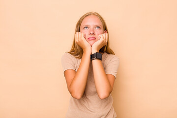 Caucasian teen girl isolated on beige background crying, unhappy with something, agony and...