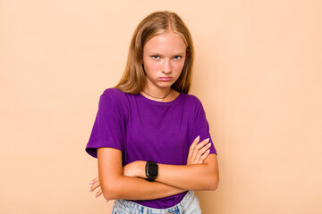 Caucasian teen girl isolated on beige background frowning face in displeasure, keeps arms folded.