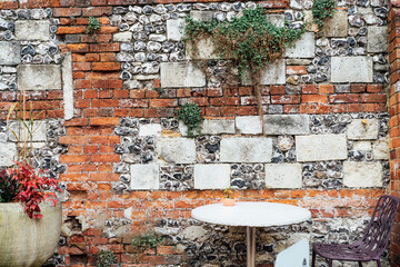 Stone cafe table and modern chair near the old brick and stone wall with growing greenery. Old town cafe with a vintage feel. Selective focus, copy space.