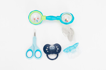Items for baby care on a white background: scissors, rattles, teether, pacifiers