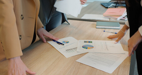 Close up hands of businesswomen analyzing income charts and graphs on office desk selecting them in folders. Close up womens hands exchanging documents. Business Concept.