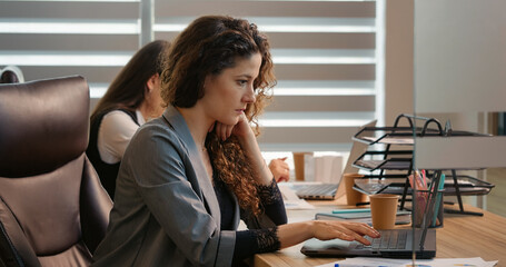 Caucasian business woman working at computer in office making victory gesture receives good news...