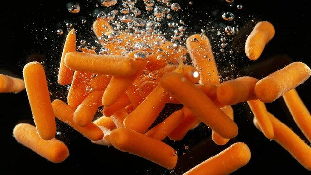 Super slow motion of falling baby carrot into water. Isolated on black background. Filmed on high speed cinema camera, 1000fps. Speed ramp effect.