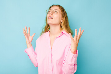 Fototapeta premium Young caucasian woman isolated on blue background screaming to the sky, looking up, frustrated.