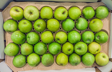 A lot of green apples lie on the counter of the market. Open shelves, showcases. Healthy organic food