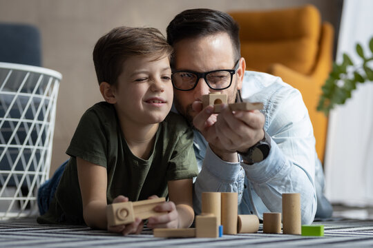 Father and son playing with wooden toys in living room