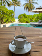 Cup of coffee on a table by the pool