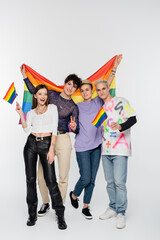 cheerful friends of diverse identity standing with lgbtq flags on grey background.