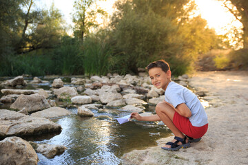 child plays in the river surrounded by nature