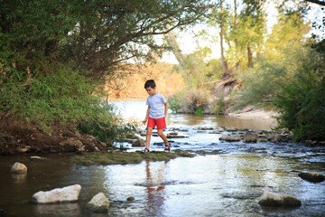 Fototapeta na wymiar child plays in the river surrounded by nature