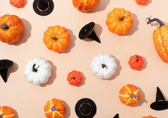 pattern of colorful artificial pumpkins and halloween hats on orange background