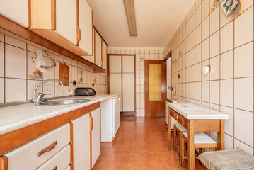 Antique kitchen with edge wood cabinets, folding table with stools, and light brown flooring