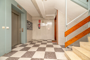 Landing between floors of a building with terrazzo stairs and elevator with stainless steel doors