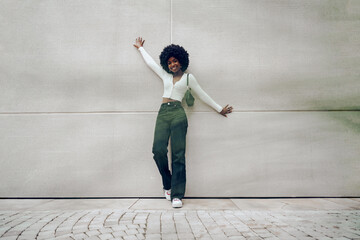 Black woman with afro hair posing in front of a gray concrete wall