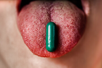 Young woman taking green pill, closeup. 