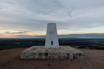 Marker at mountaintop in English countryside at dawn / sunrise 