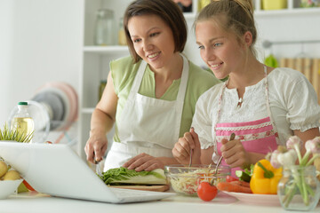 Beautiful girl with her mother preparing a salad in the kitchen