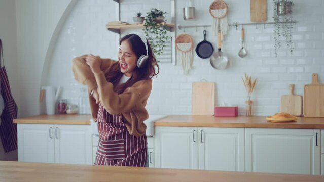 Slow motion of happy young asian woman dancing with headphones at home having fun relaxing with funny dance moves enjoying freedom on weekend morning. People, Lifestyle and joy concept.