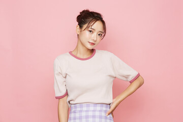 スポーティなファッションをした若い女性のピンク背景のポートレート