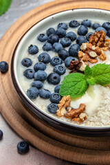 oatmeal porridge with ripe blueberries, nuts and honey healthy breakfast on rustic wooden background. close up