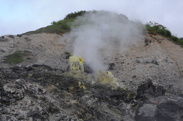 Fumarole emitting smoke, fume and sulphur steam in mountain valley at Tamagawa Onsen Hot spring in...